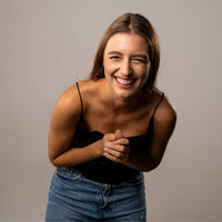 Thumbnail for Smiling woman with brown hair wearing a black top and jeans, conveying joy and happiness.