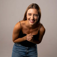 Thumbnail for Laughing woman in a black top and denim shorts, expressing joy and happiness.