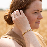 Thumbnail for Woman gently touching her Be Gorgeous, Be Yourself bracelet in gold | SKU: bgby-g