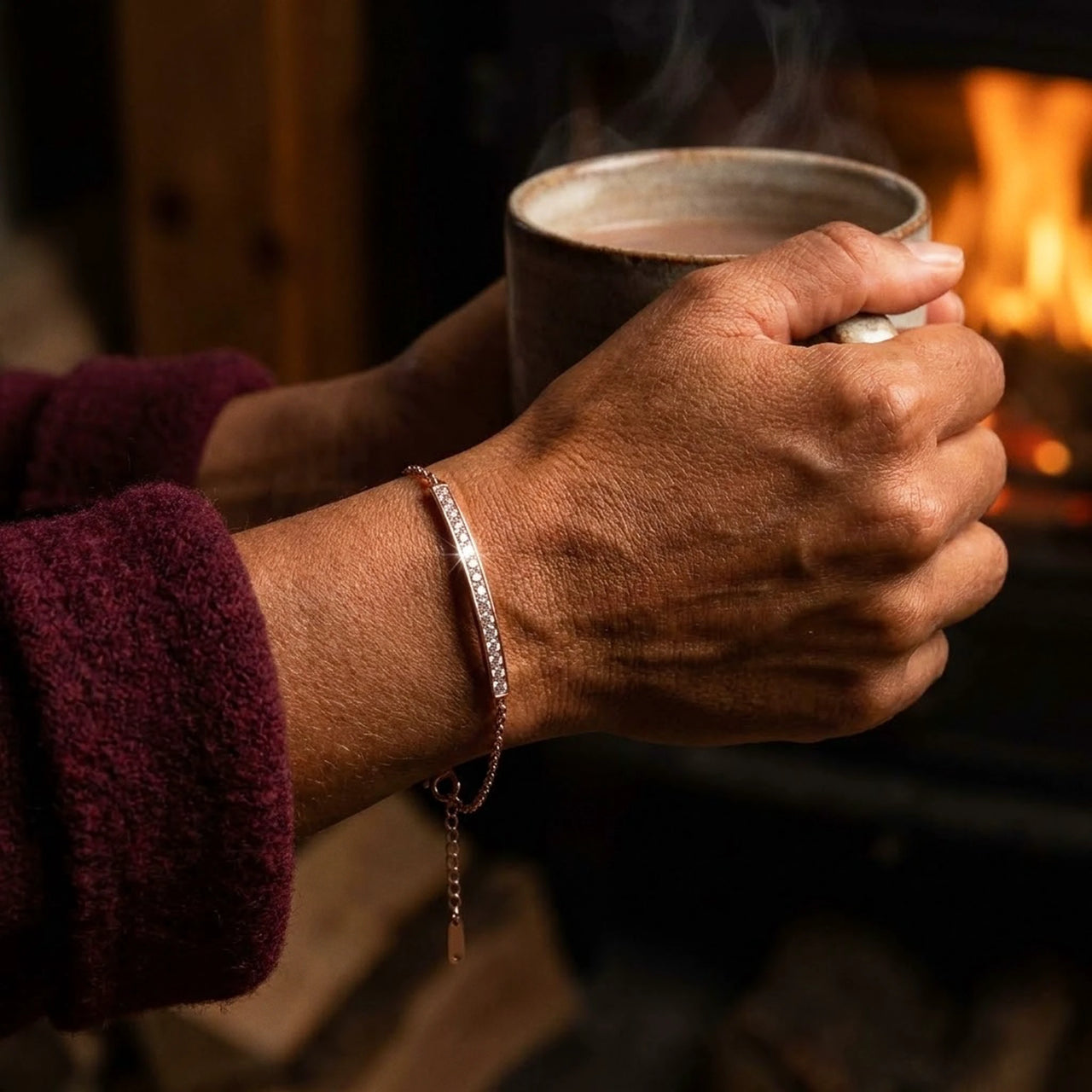 Rose gold Crystal Bar Bracelet worn while holding a warm mug in front of a fire