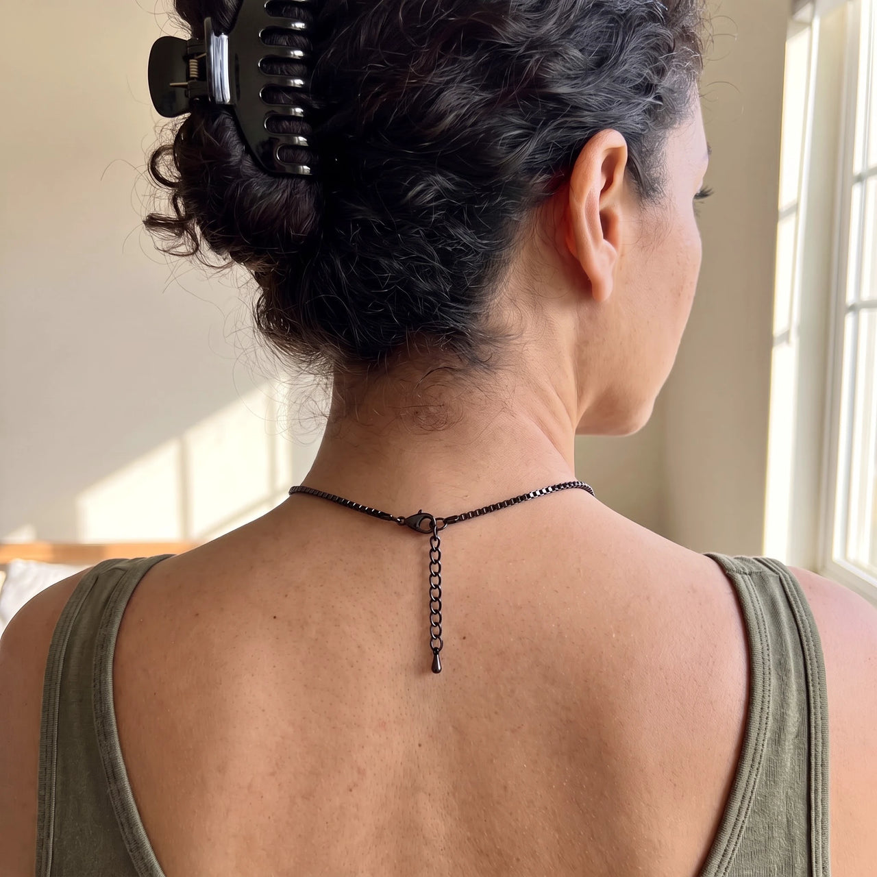 Back of the neck of a woman with a hair clip showing the clasp and extension chain of the black clover photo necklace | SKU: TPH-CLVN-BLACK