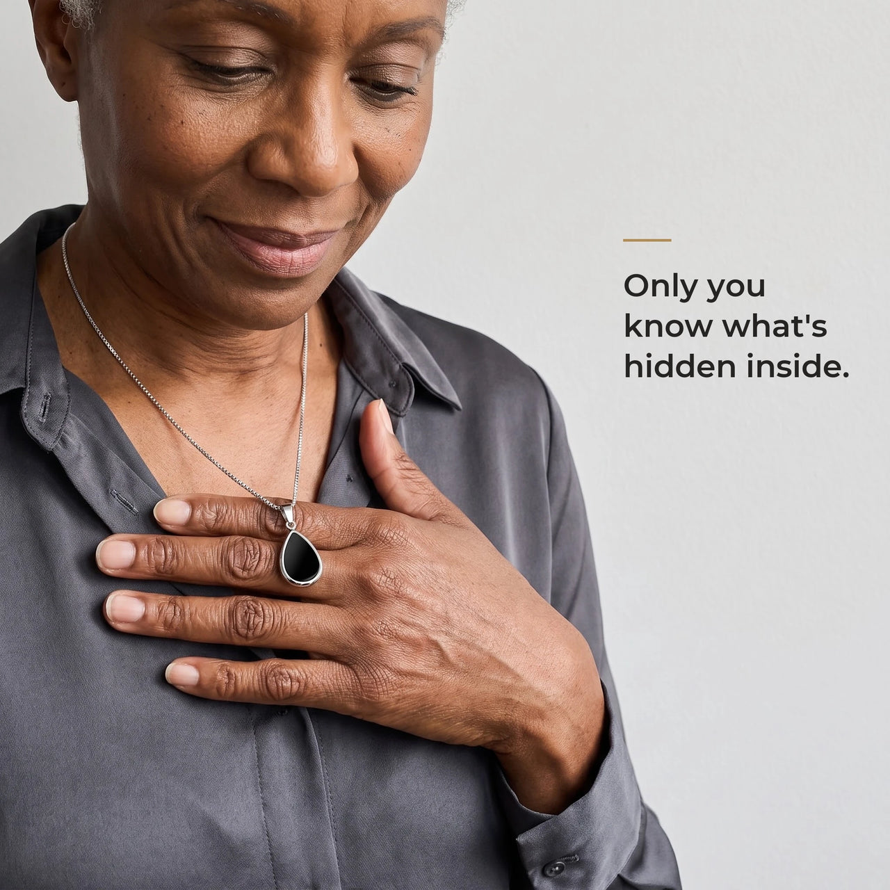 Woman holding the black teardrop pendant on its silver chain against her chest, only she knows the photo inside | SKU: TPH-DRPN-SILVER