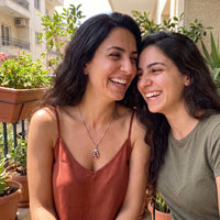 Thumbnail for Two women laughing together on a balcony, one wearing the silver secret drop photo necklace | SKU: TPH-DRPN-SILVER