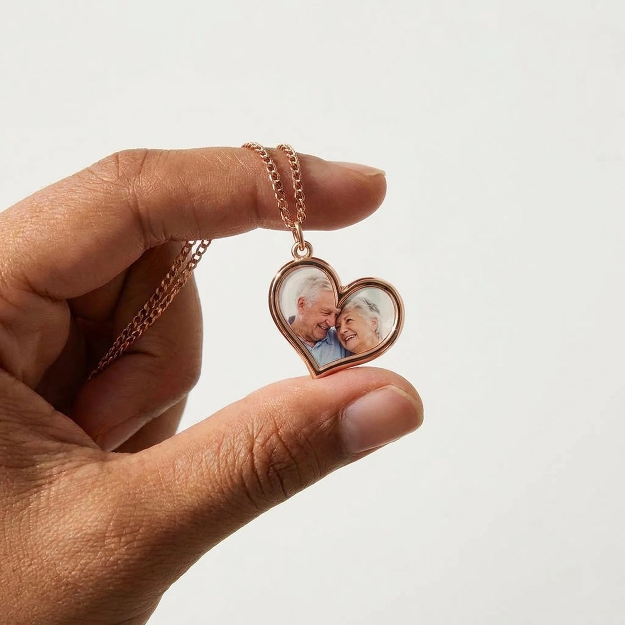 Rose gold heart pendant held between two fingers, real small size, grandparents' photo inside | SKU: TPH-HRTN-ROSEGOLD