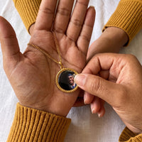 Thumbnail for Thumb warming the gold round pendant: the hidden photo appears under the thumb while the rest stays black | SKU: TPH-RNDN-GOLD